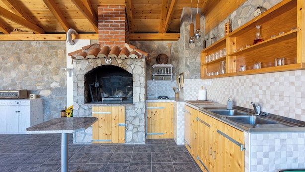 Una cocina rústica con chimenea de piedra, armarios de madera y salpicadero de azulejos.