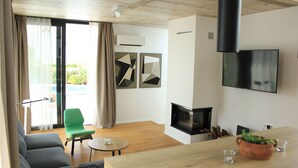 Un salon moderne avec un canapé, un fauteuil vert, une cheminée et un téléviseur fixé au mur.