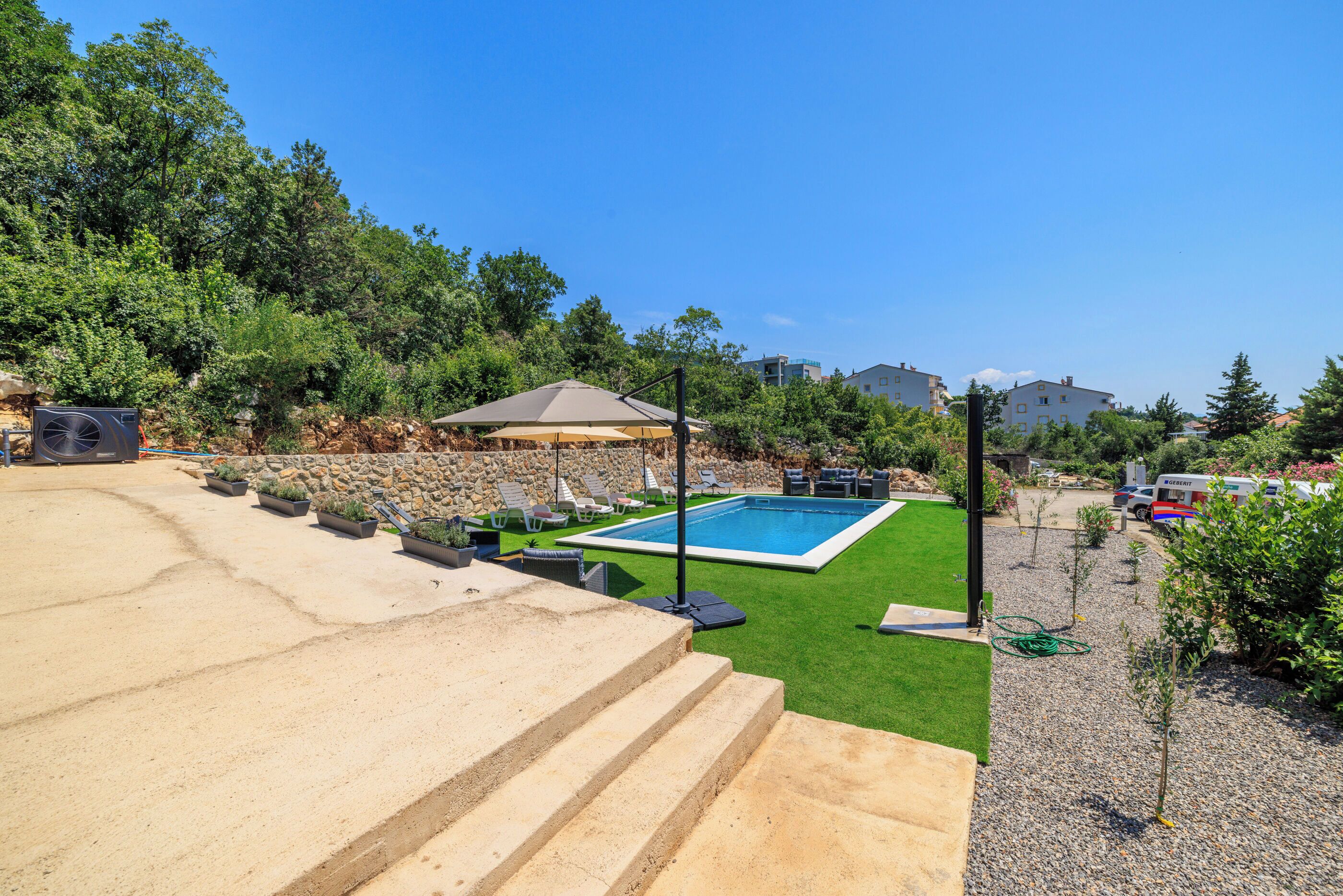 A backyard with a swimming pool, steps, and a patio area with outdoor furniture.