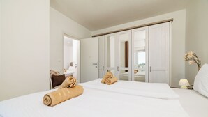 Ein Hotelzimmer mit einem Bett, einem Kleiderschrank, einem Schreibtisch mit Stuhl sowie einem Nachttisch mit Lampe.