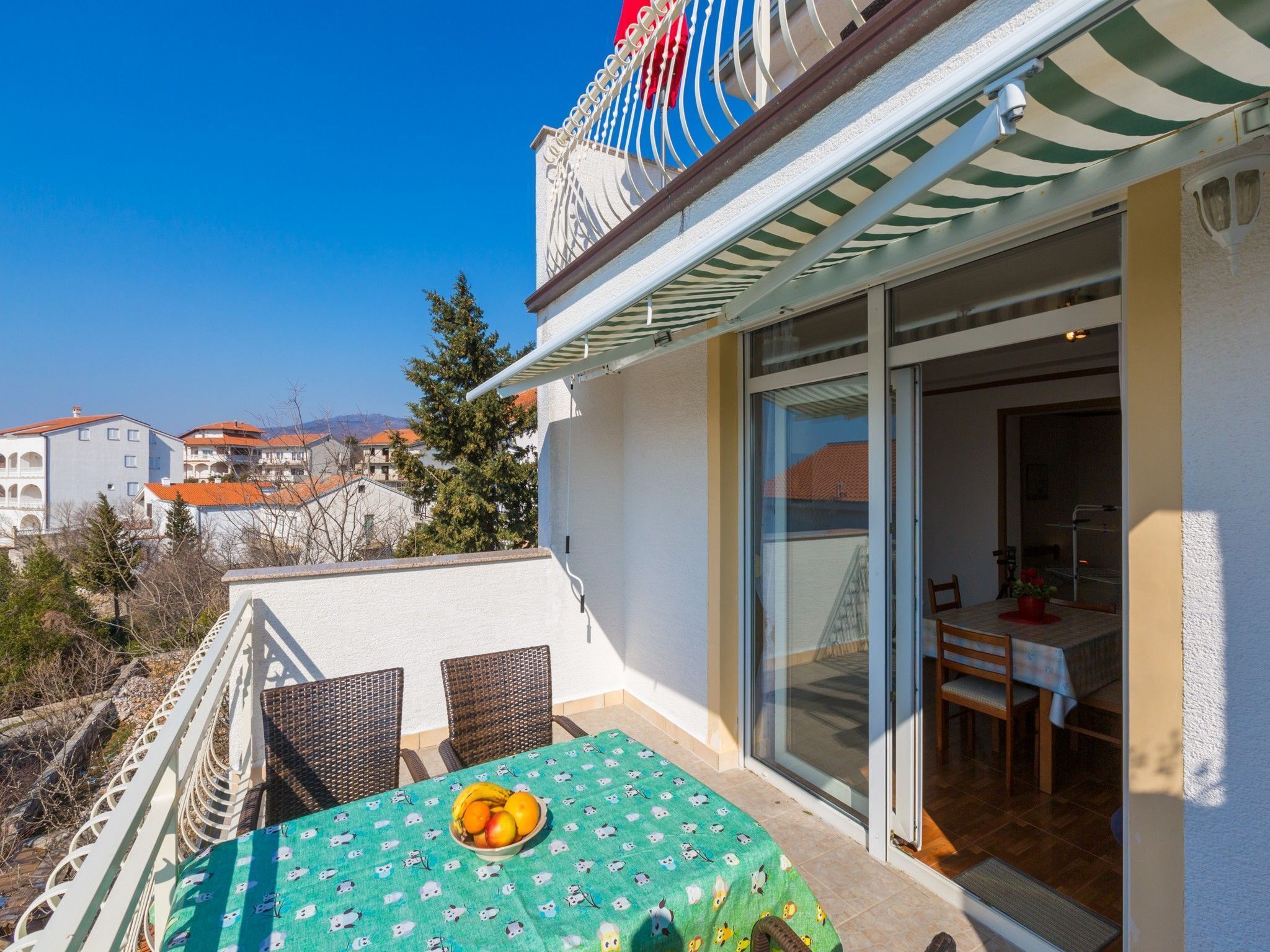 Ein Balkon mit Tisch und Stühlen, einer Obstschale und Blick auf die umliegenden Gebäude.