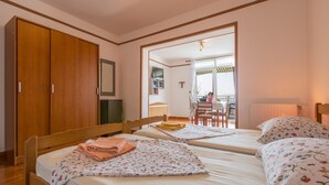 Un dormitorio con dos camas, un armario de madera y un espejo que refleja una zona de comedor.