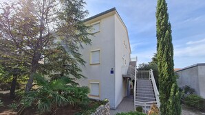 Un edificio de dos pisos con un camino de piedra que lleva a una entrada portonada.