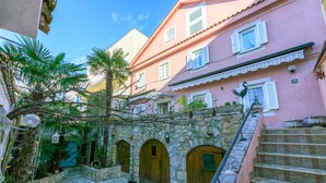 A courtyard with stone walls, wooden doors, and a staircase leading to an upper level. - Apartments Villa 7 (Crikvenica)