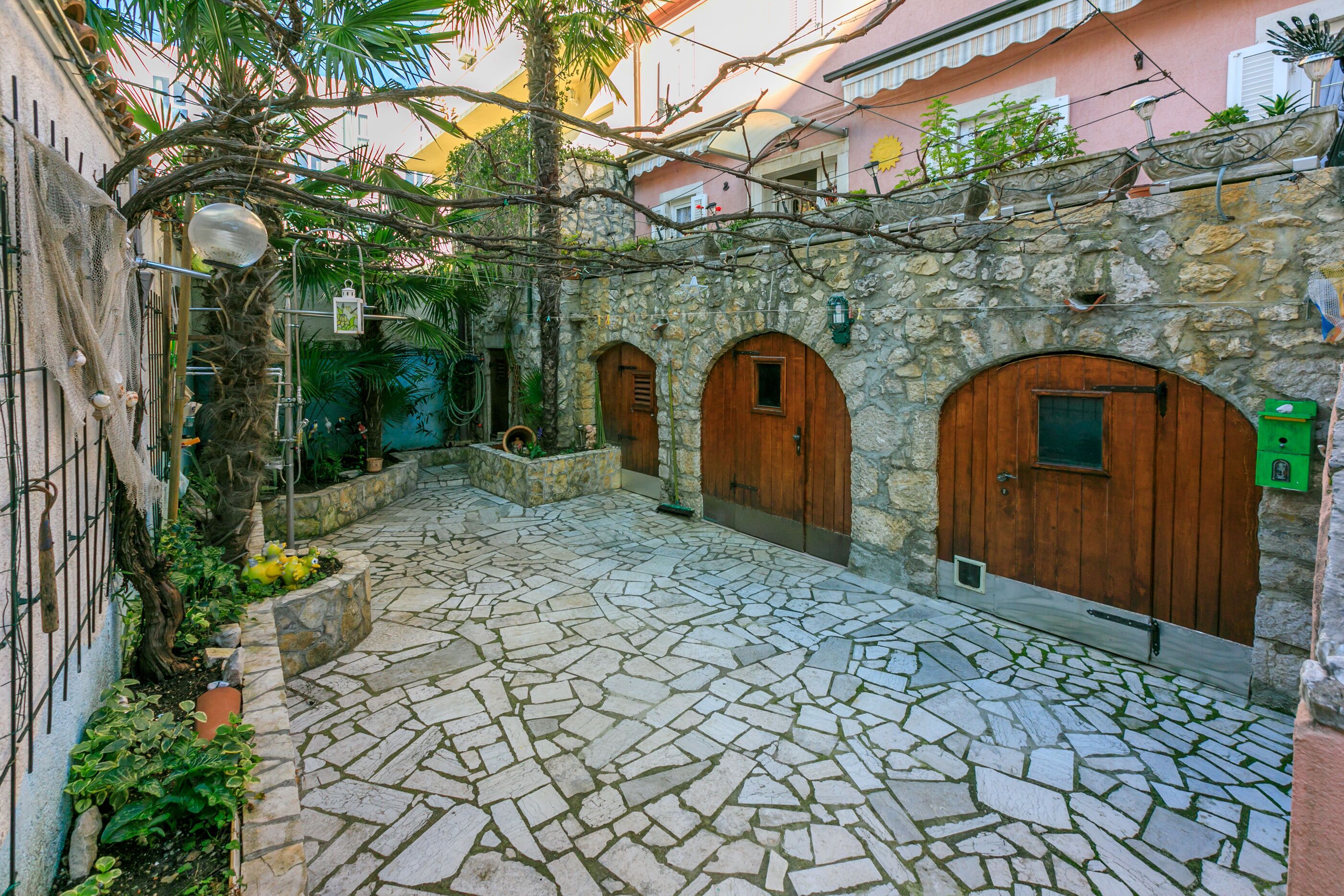 A courtyard with stone flooring, wooden doors, and a stone wall.