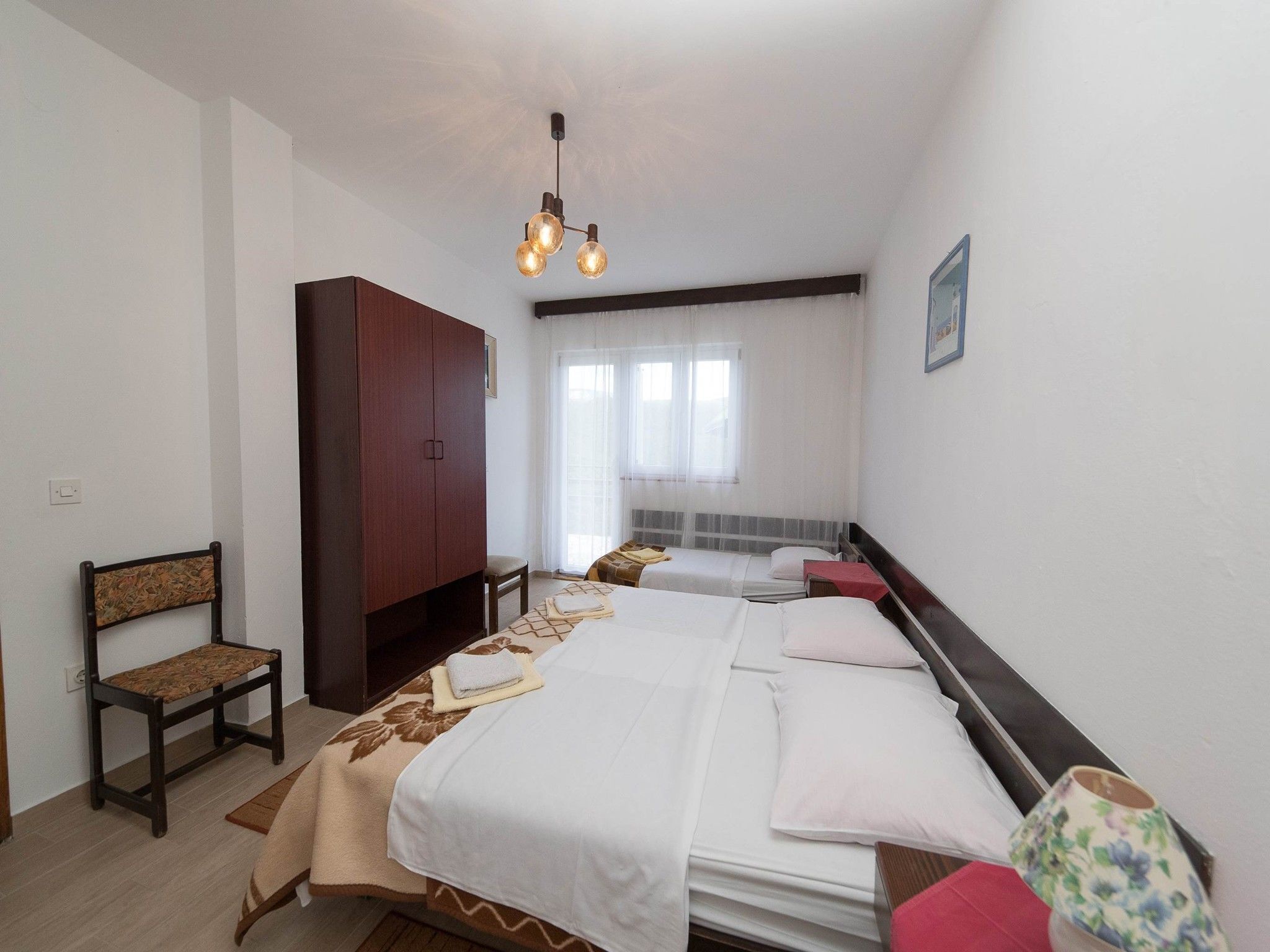 Una camera d'albergo con un letto grande, un armadio, una sedia e una finestra con tende.