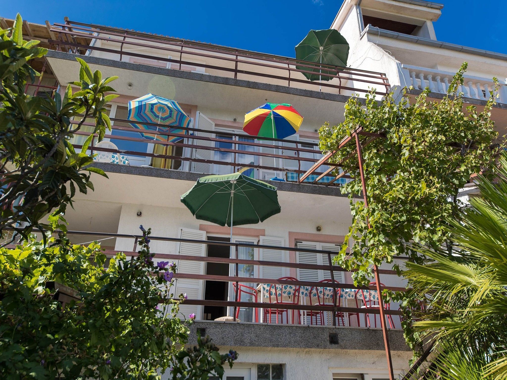 A multi-story building with balconies, some with umbrellas.