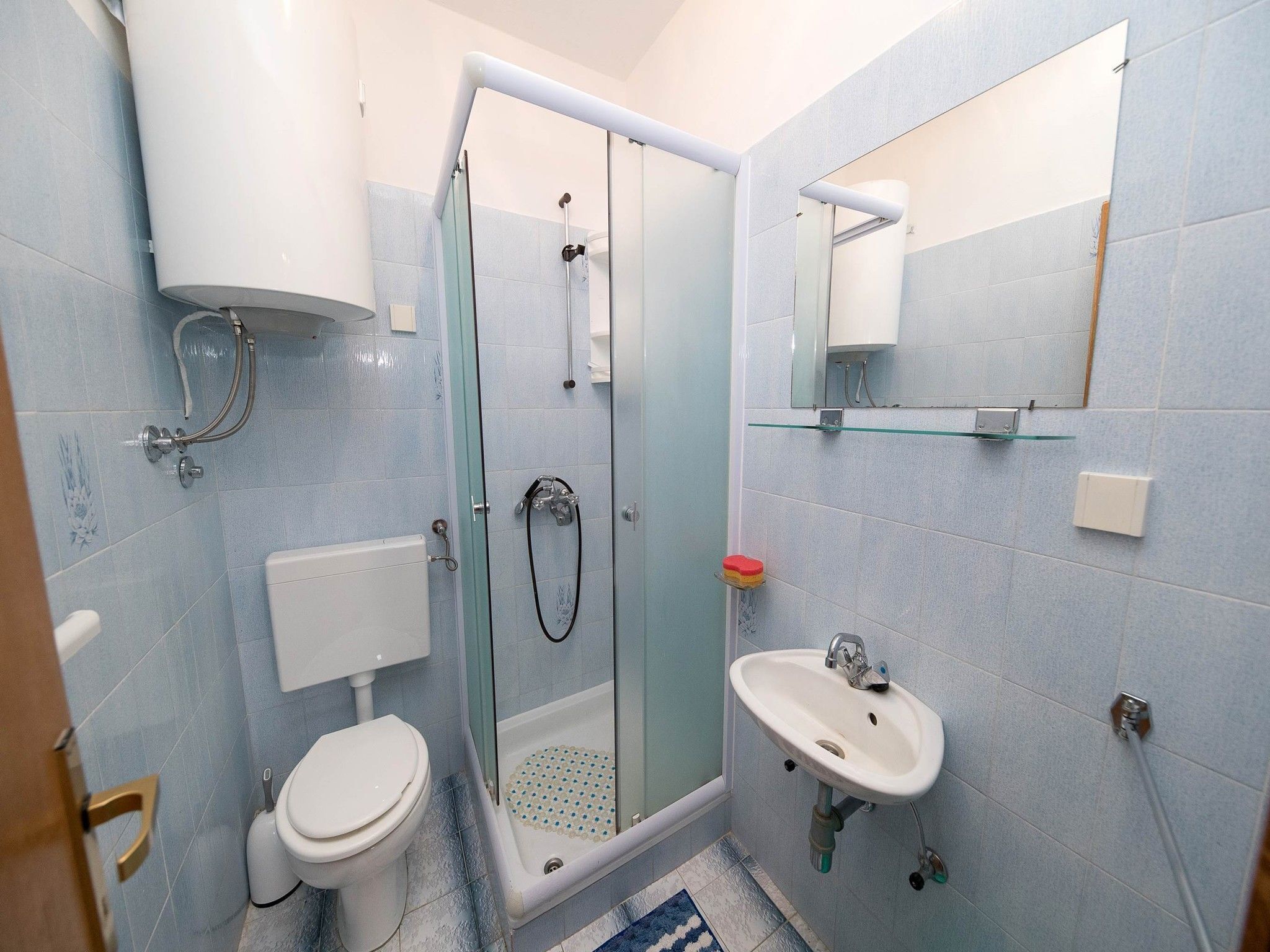 Une salle de bain comprenant des toilettes, une douche à parois de verre, un lavabo et un miroir.