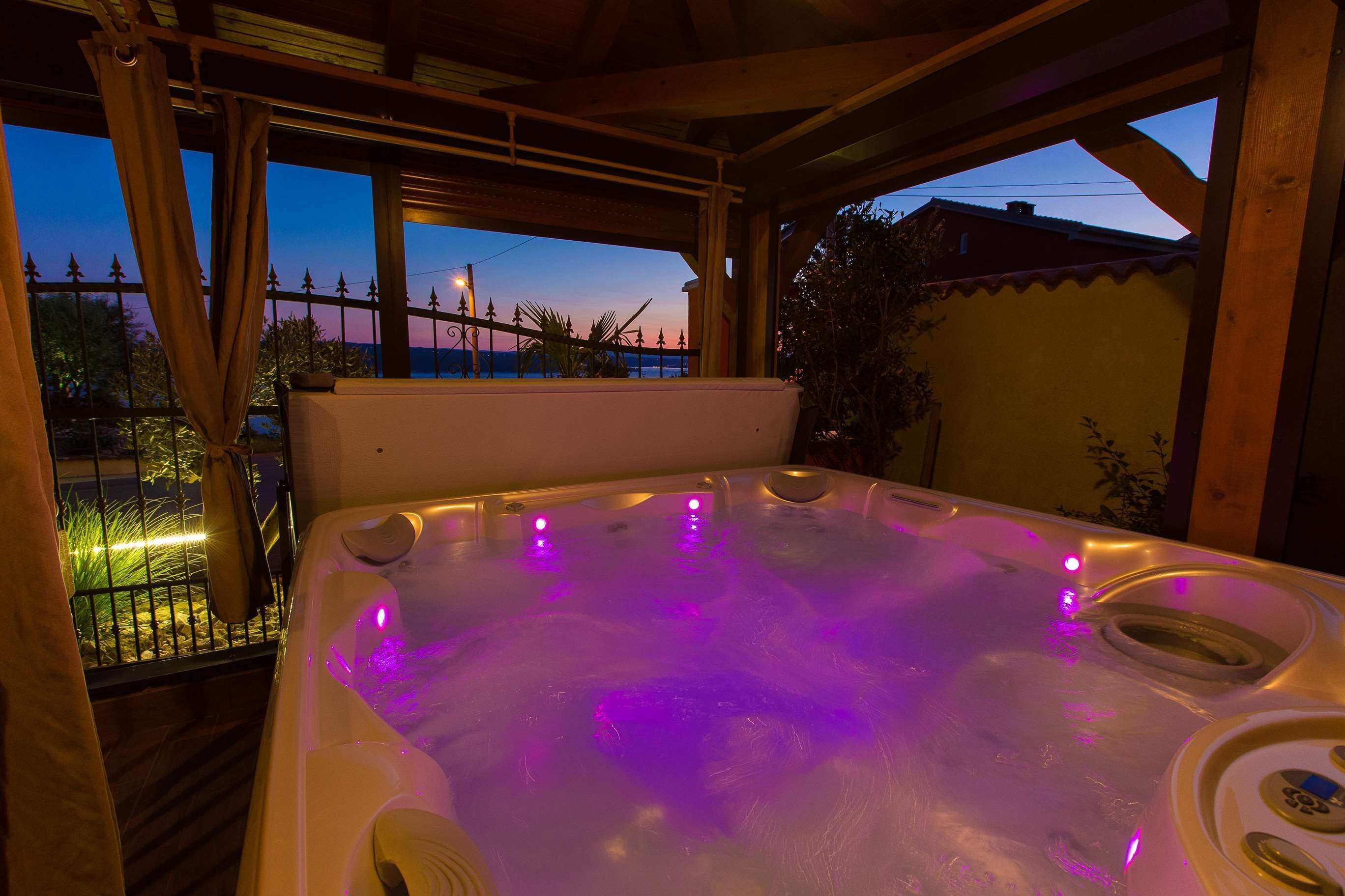 A hot tub with a wooden deck and a view of the sunset.