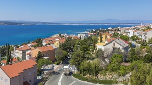 Uma vila costeira com edifícios, uma estrada e vista para o mar e montanhas.