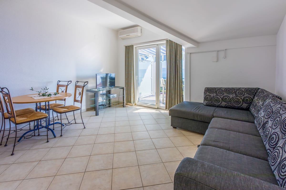 A living room with a sofa, a dining table with chairs, and a TV.