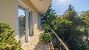 Un balcon avec un sol en pierre, des portes vitrées et des plantes en pot.