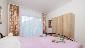 Une chambre à coucher avec un lit, une armoire en bois et une fenêtre avec des rideaux.