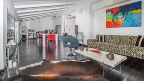 A modern living room with a patterned sofa, a glass coffee table, and a vibrant abstract painting on the wall. - Apartments Adriatic (Crikvenica)