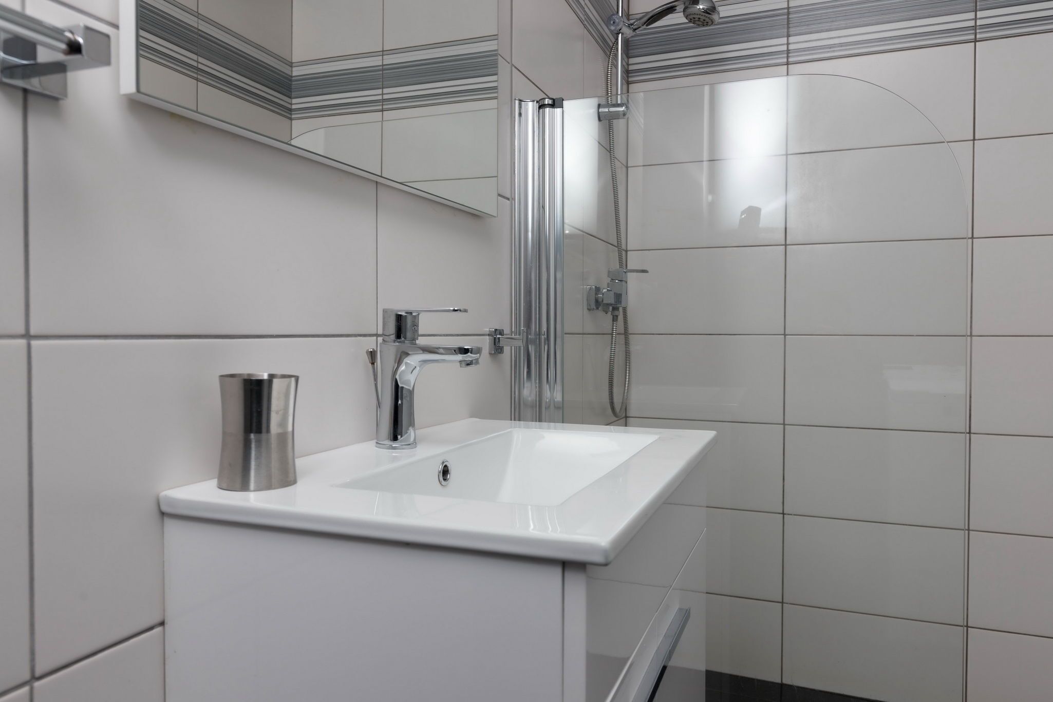 Une salle de bain moderne avec un lavabo blanc, un robinet chromé et une douche à parois de verre.