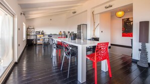 A modern kitchen with a white island, black and red chairs, and a dining area. - Apartments Adriatic (Crikvenica)