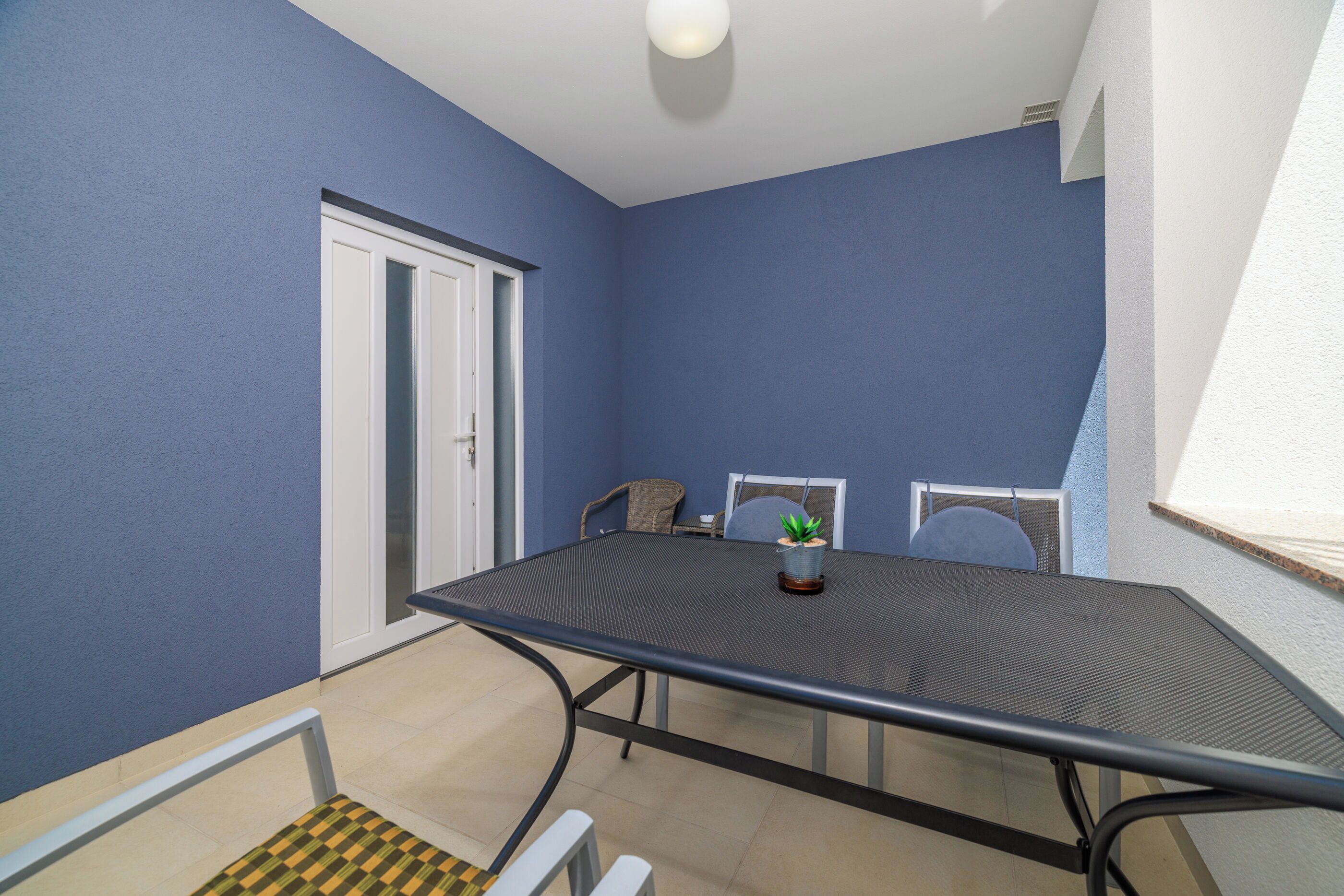 Een vergaderzaal met een tafel, stoelen, een plant in pot en een deur.