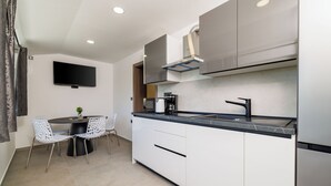 Een moderne keuken met een flatscreentelevisie, een eettafel met stoelen en een inbouwoven.