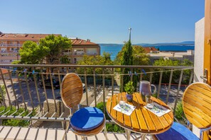 Un balcon avec des meubles en bois, une vue sur la mer et des bâtiments en arrière-plan.