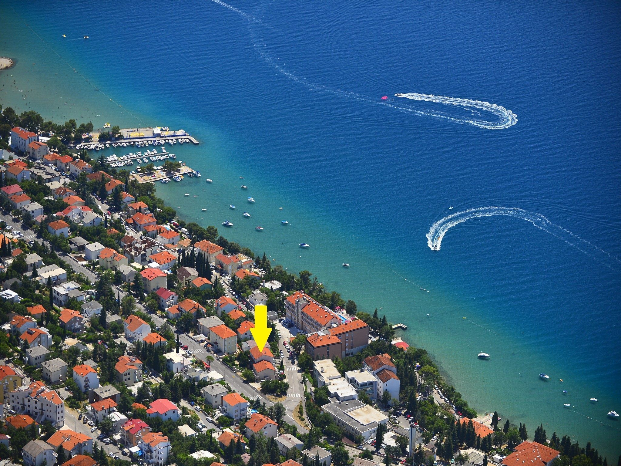 An aerial view of a coastal town with buildings, boats, and a marina.