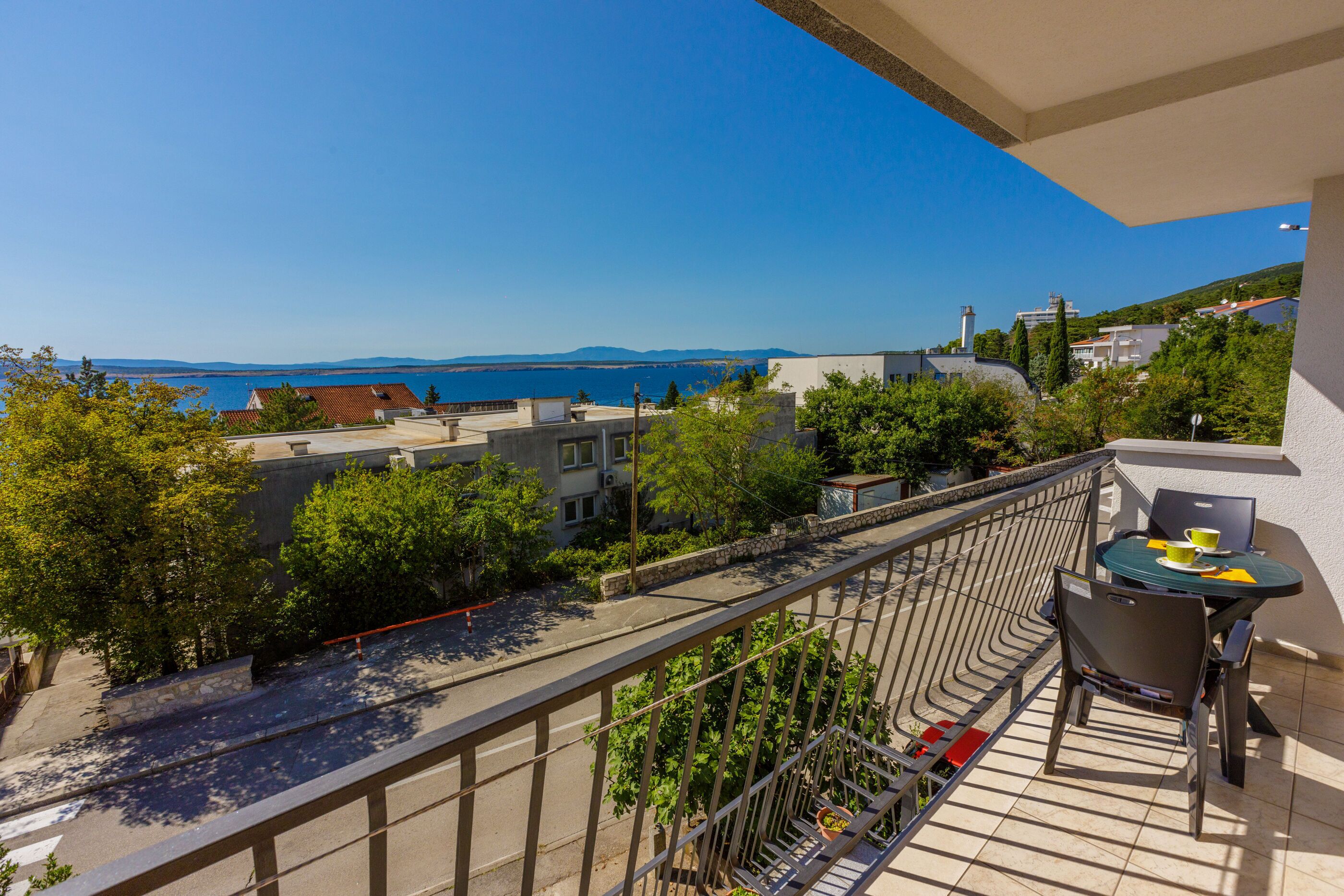 Un balcon avec vue sur la mer, une table avec des chaises et une rambarde.