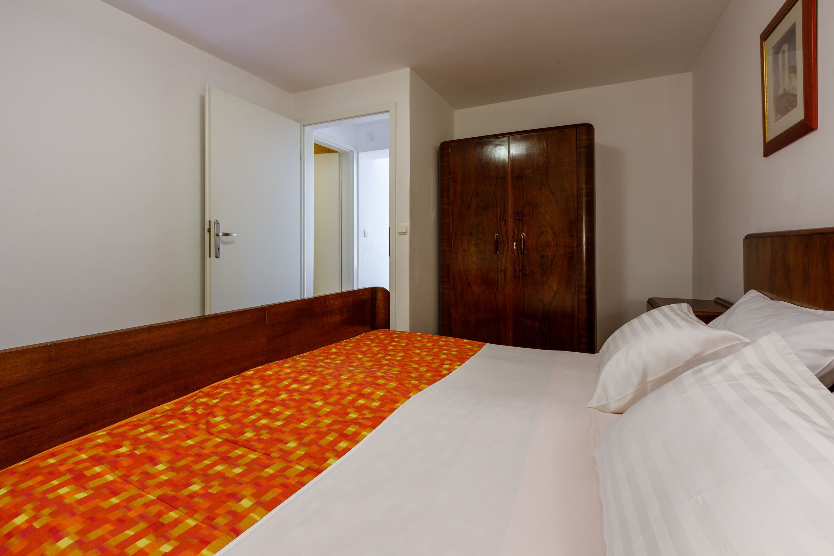 A bedroom with a bed, a wardrobe, and a nightstand.