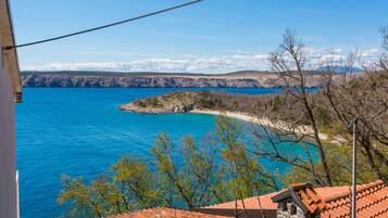 A coastal view with a clear blue sea, rocky cliffs, and a small island.