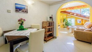 A dining area with a table, chairs, a vase of flowers, and a painting on the wall. - Apartments Senka (Dramalj)