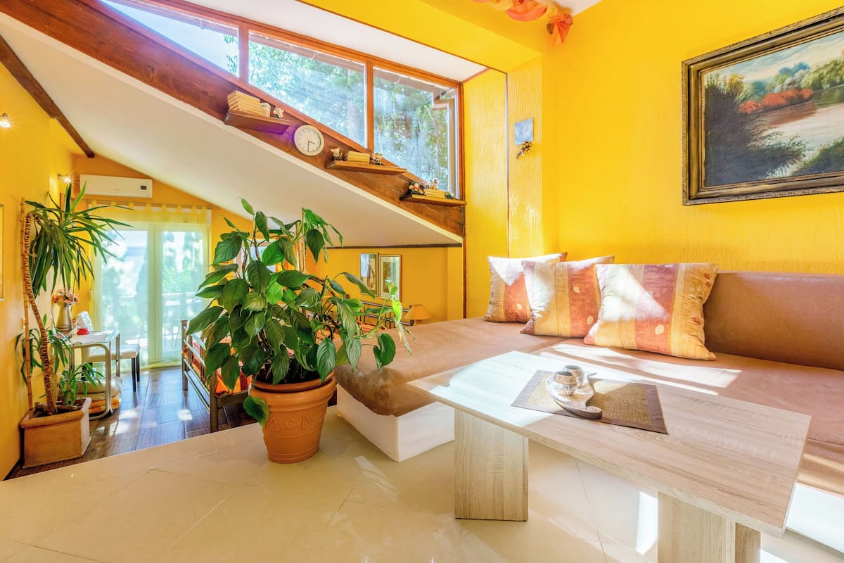 A bright yellow room with a staircase, a sofa, and a coffee table.