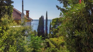 A house with a tiled roof, a chimney, and a view of the sea. - Apartments Senka (Dramalj)