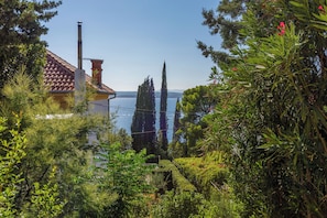 A coastal property with a tiled roof, a chimney, and a view of the sea. - Apartments Senka (Crikvenica)