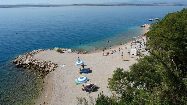 A beach with clear water, umbrellas, and people. - Apartments Senka (Dramalj)