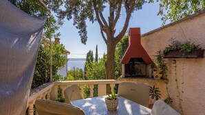A patio with a table and chairs, a barbecue grill, and a view of the sea. - Apartments Senka (Dramalj)