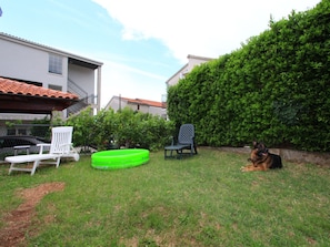 A grassy backyard with two lounge chairs, a green inflatable pool, and a dog. - Apartment Giardino (Crikvenica)