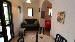A living room with a sofa, a dining table with chairs, a wine bottle, and a glass. - Apartment Giardino (Selce)
