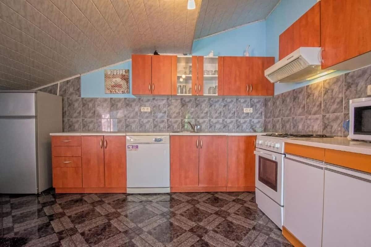 A compact kitchen with wooden cabinets, a built-in dishwasher, and a microwave.