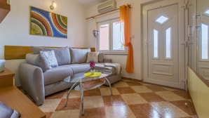 Una sala de estar con un sofá, una mesa de centro de vidrio y un cuadro en la pared.