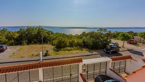 Zona residencial con vista a un cuerpo de agua, coches aparcados y cielo despejado.