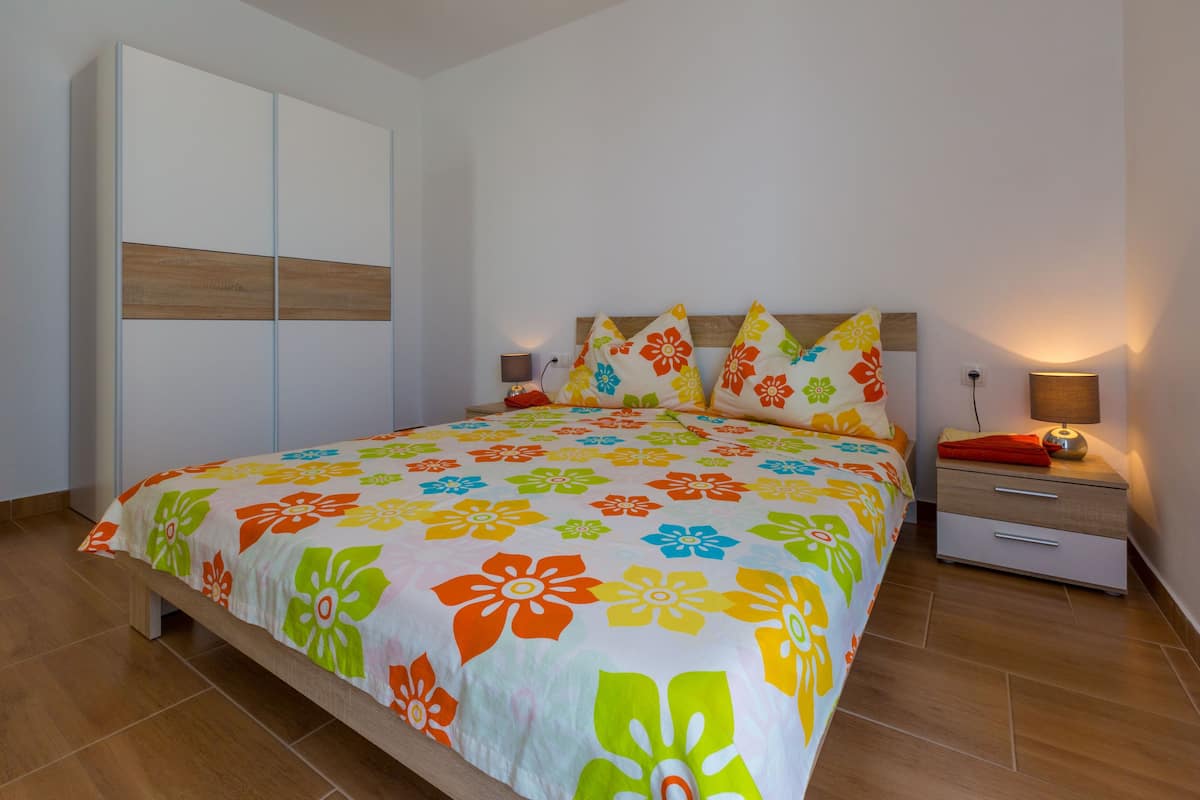 A bedroom with a bed, nightstands, a wardrobe, and a lamp.
