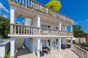 A two-story building with a balcony, outdoor seating area, and a yellow umbrella.