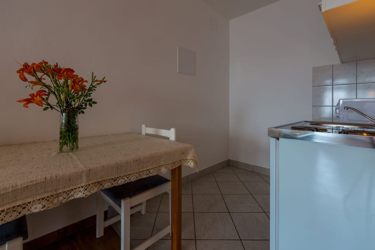 A kitchen with a white table, a vase with flowers, and a tiled backsplash.