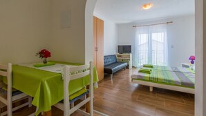 Une pièce comprenant une table à manger, un canapé, un téléviseur et un lit.
