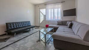 Un salon moderne avec un canapé, une table basse en verre et un téléviseur fixé au mur.