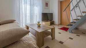 Un salon moderne avec un canapé, une table basse en bois, un téléviseur et un escalier.