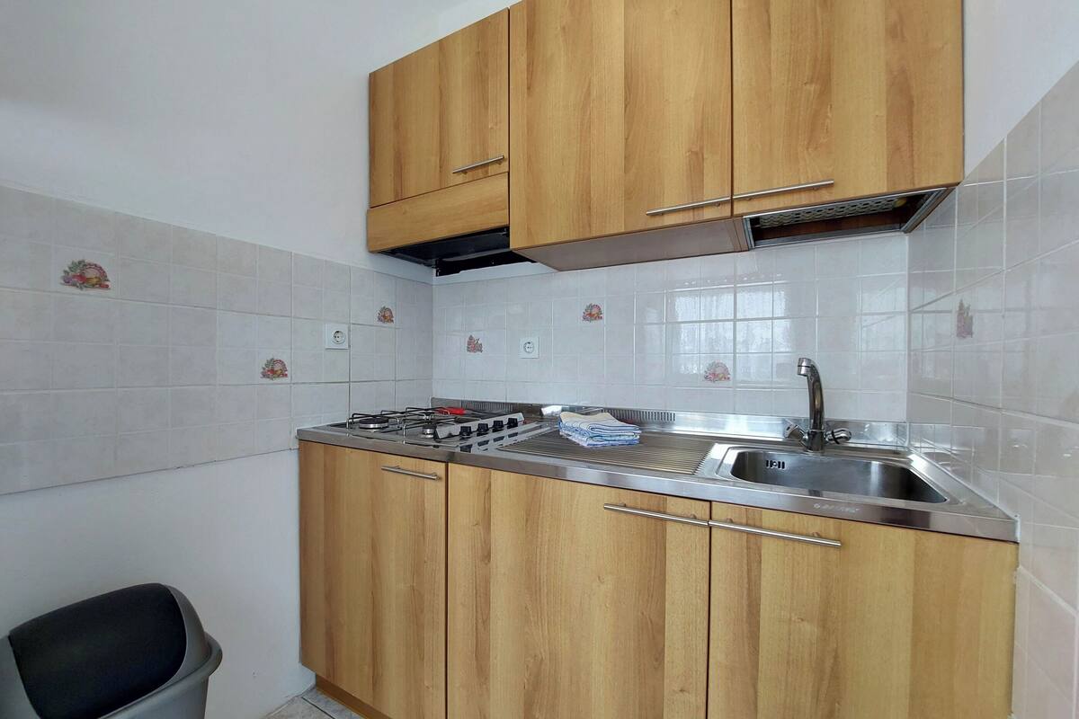 Een keuken met houten kastjes, een roestvrijstalen spoelbak en een gasfornuis.