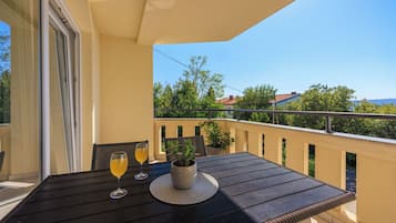 Un balcón con una mesa, dos copas de vino y una maceta.