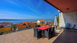 Une terrasse avec une table et des chaises rouges, un mur en pierre et une vue sur la mer.
