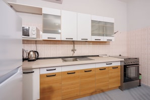 A kitchen with white cabinets, a stainless steel oven, and a sink. - Apartments Davorka (Crikvenica)