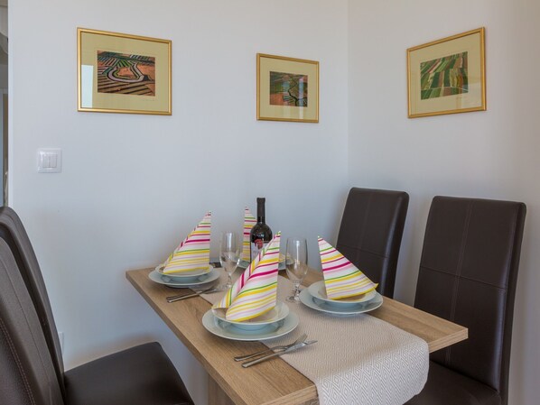A dining table set with striped napkins, wine glasses, and a bottle.