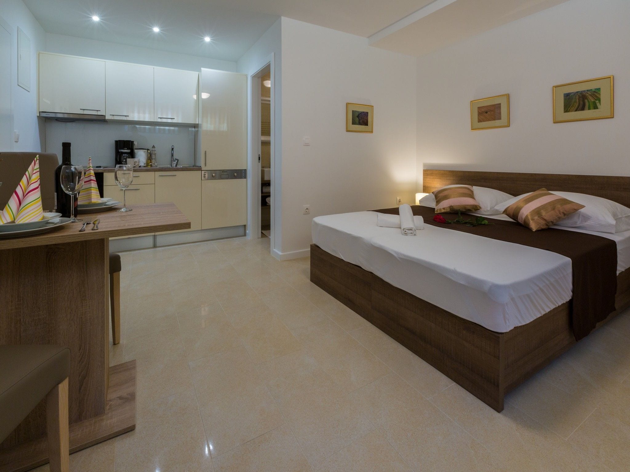 A hotel room with a bed, bedside table, and a kitchenette.
